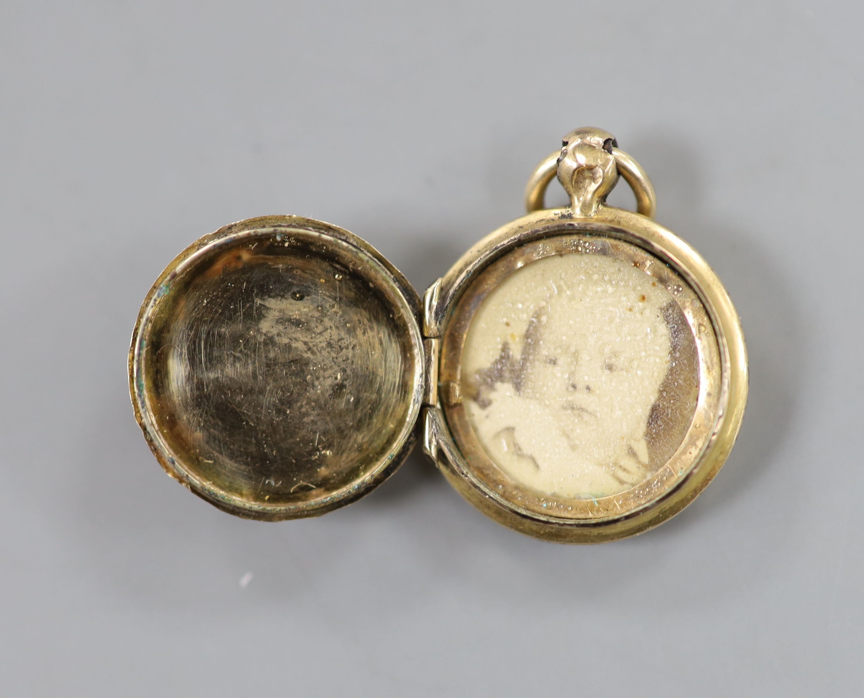 A small early 20th century yellow metal and enamel pendant locket, 18mm, together with a very small horse head pendant on an 18kt fine link chain, gross 5.3 grams.